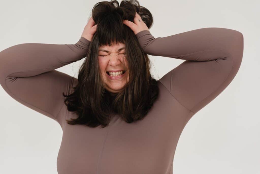 woman itching scalp with hands in hair